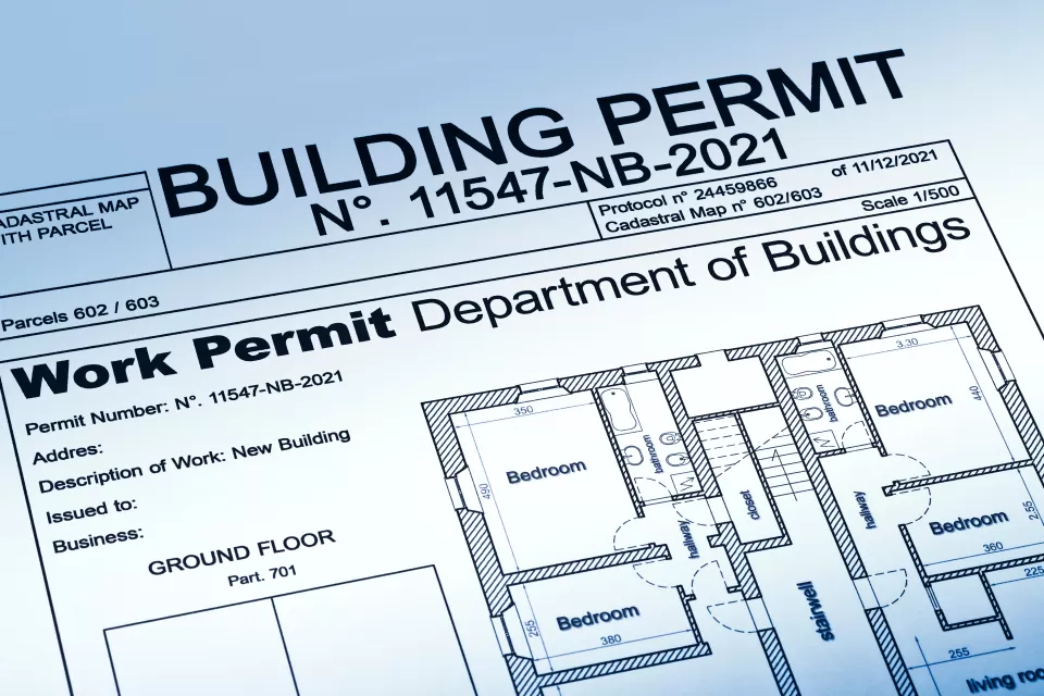 View of a housing permit document with a home blueprint, stamped "approved."